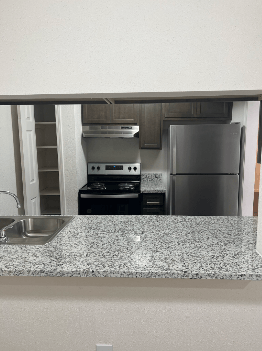 a kitchen with a granite counter top and a stainless steel refrigerator