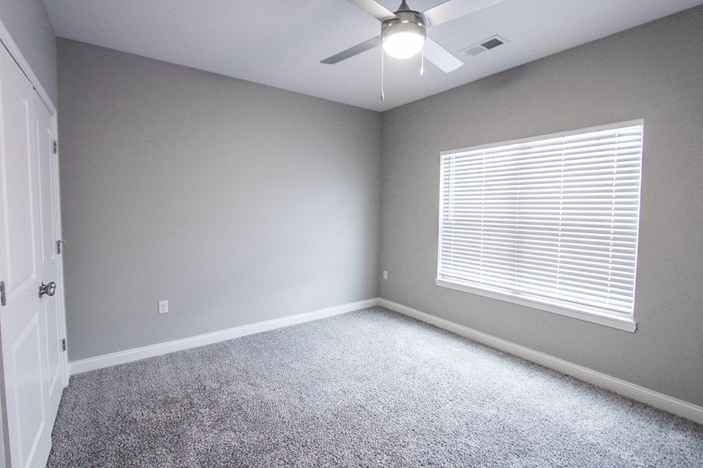 an empty room with a ceiling fan and a window