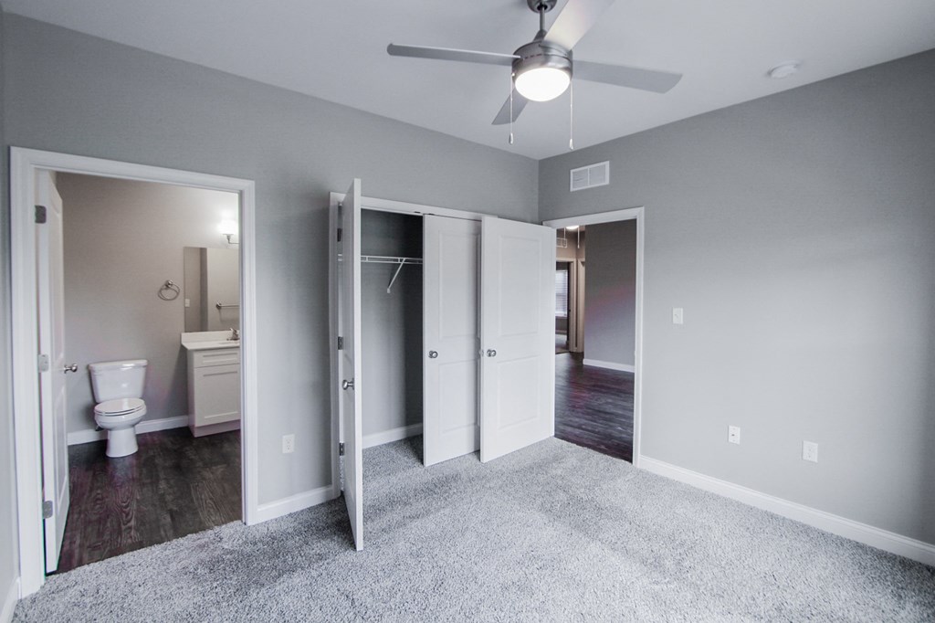 an empty bedroom with a ceiling fan and a bathroom