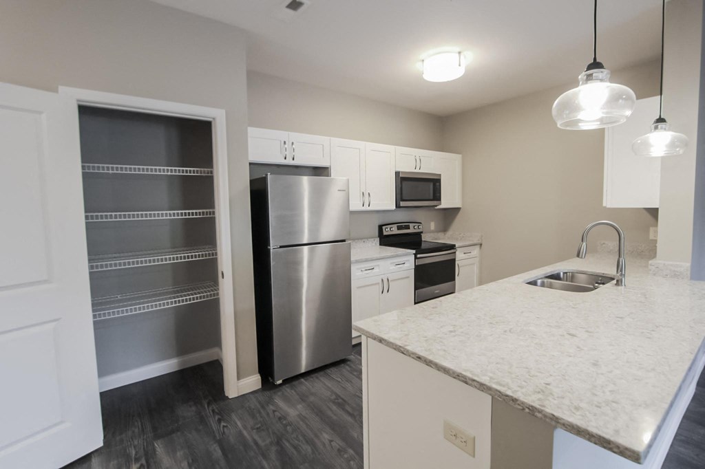 a kitchen with a marble counter top and a stainless steel refrigerator