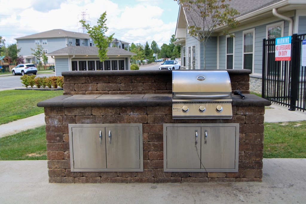a brick bar with a grill and cabinets in front of a house