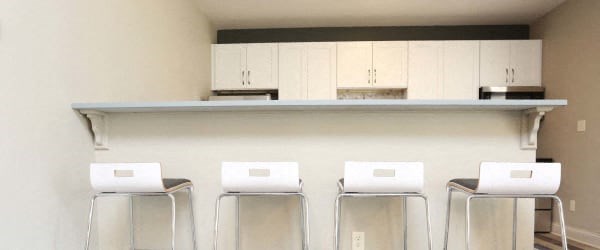 a row of stools in front of a bar with white cabinets