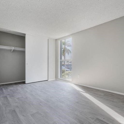 an empty living room with a window and a closet at The Arches Apartments, California, 92021