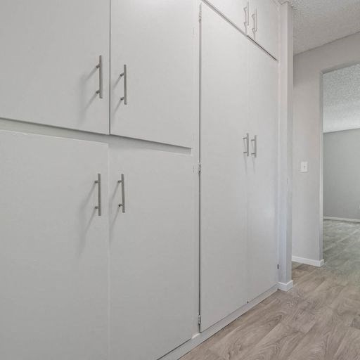 a row of white cabinets in the corner of a room at The Arches Apartments, El Cajon