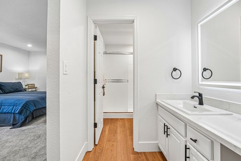 A white bathroom with a blue bed in the bedroom.