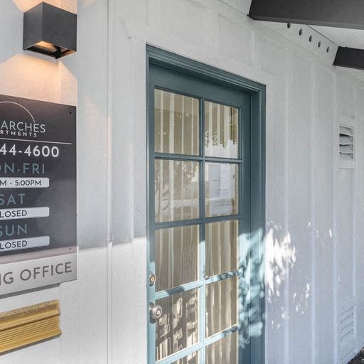 the front door of a white building with a glass door at The Arches Apartments, El Cajon, CA 92021