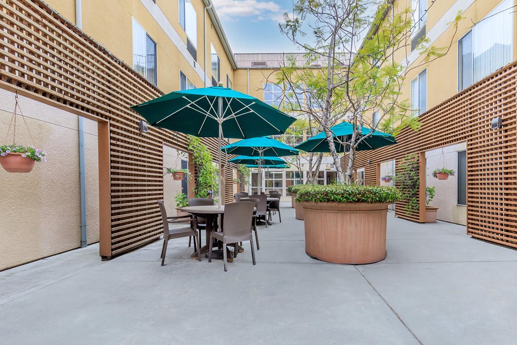 A Patio With Tables And Chairs And Umbrellas at Atrium Garden Apartment Homes, LLC, California