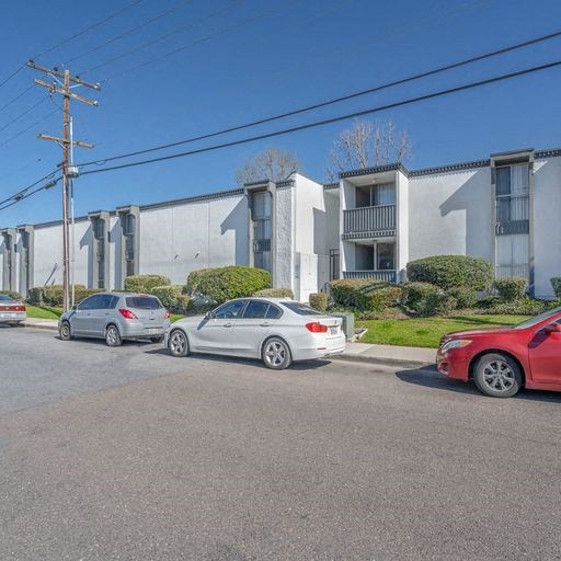 a group of cars parked in front of an apartment building at The Arches Apartments, California
