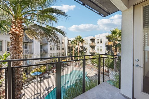 A balcony with a pool and palm trees.