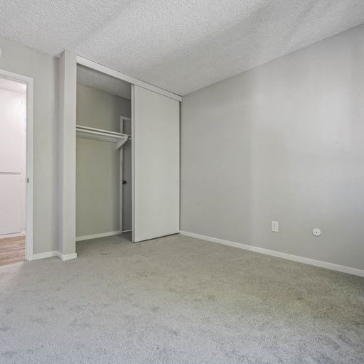 an empty living room with an open door to a closet at The Arches Apartments, El Cajon California