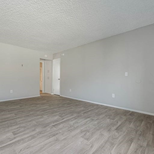 an empty living room with a wood floor at The Arches Apartments, El Cajon, CA