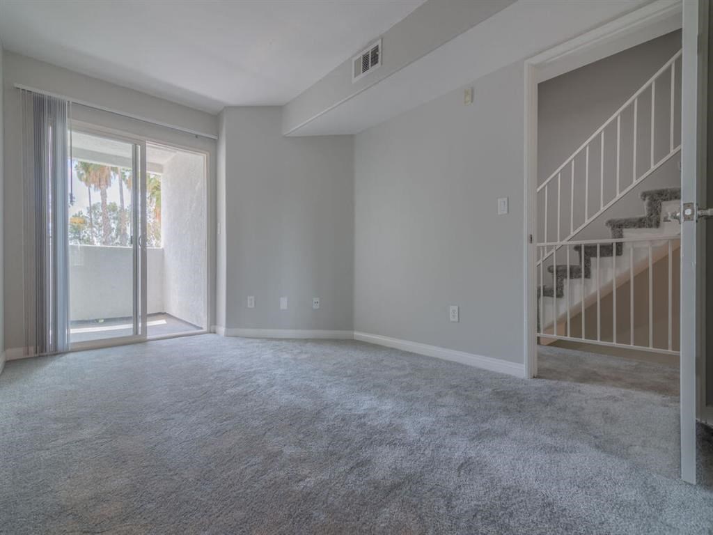 an empty living room with a sliding glass door and a staircase  at Warner Center Townhomes, Canoga Park, CA 91303