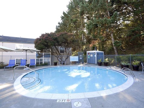 a swimming pool with chairs and a fence around it at Skyline Heights Apartments, Daly City