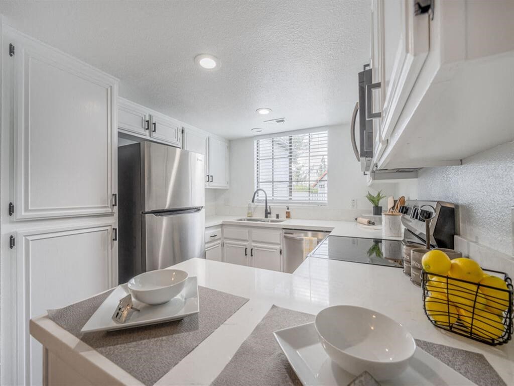 a kitchen with white cabinets and a stainless steel refrigerator  at The Resort at Encinitas Luxury Apartment Homes, Encinitas