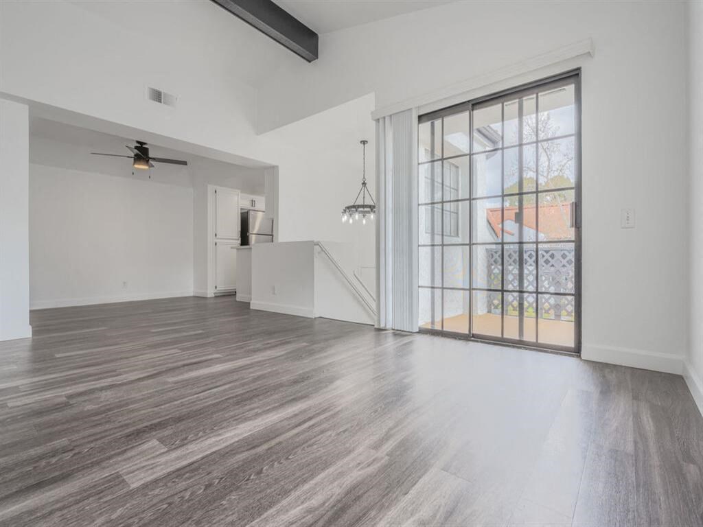 an empty living room with a large window and a staircase  at The Resort at Encinitas Luxury Apartment Homes, California