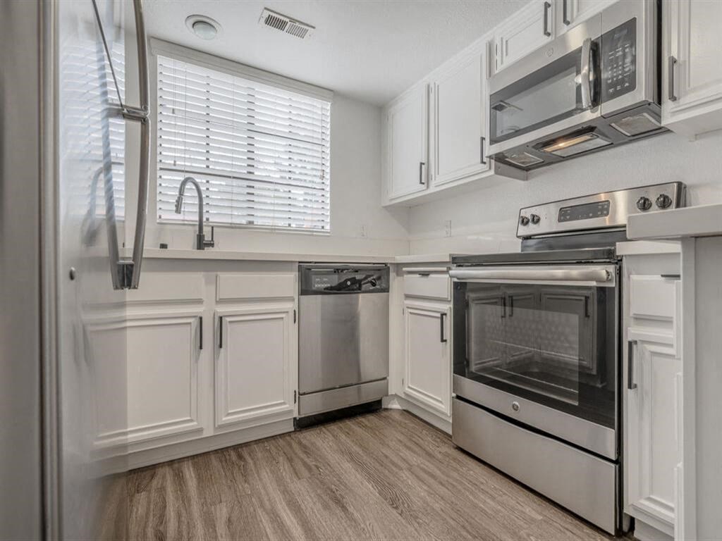 a kitchen with white cabinets and stainless steel appliances  at The Resort at Encinitas Luxury Apartment Homes, Encinitas, California