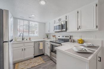 a white kitchen with white cabinets and stainless steel appliances  at The Resort at Encinitas Luxury Apartment Homes, Encinitas, CA
