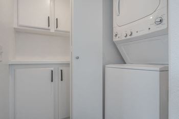 a white laundry room with white cabinets and a washer and dryer  at The Resort at Encinitas Luxury Apartment Homes, Encinitas, 92024