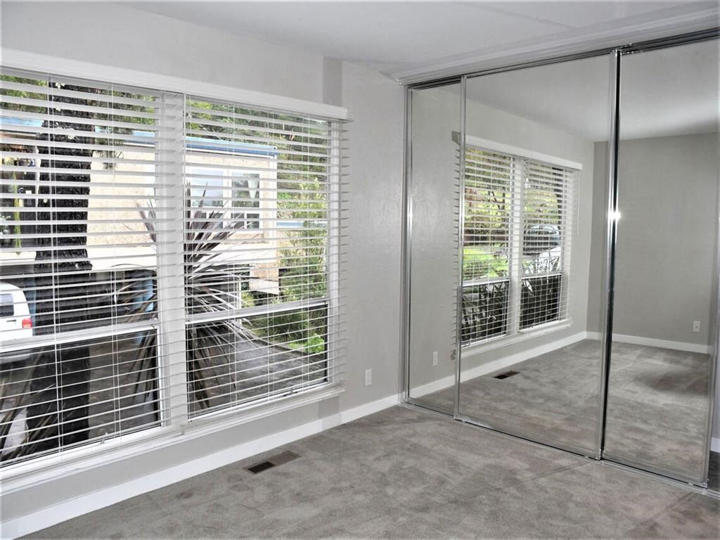 a room with a large window with blinds and a mirrored closet at Trailhead Apartments at Tam Junction, California, 94941