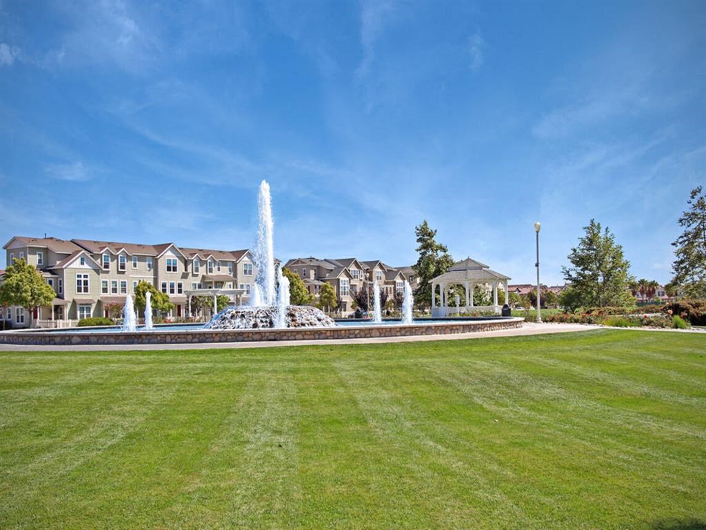 a fountain in the middle of a park with a building in the background at The Vines at Riverpark, LLC, Oxnard, 93036