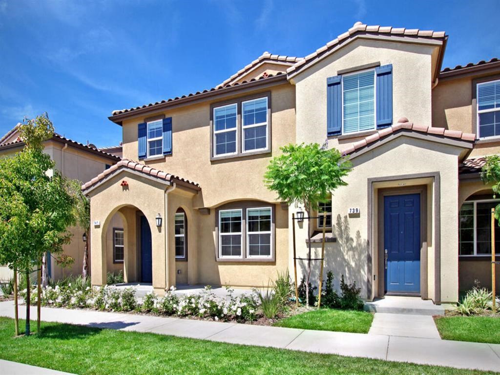 a house with a blue door and a lawn at The Vines at Riverpark, LLC, Oxnard