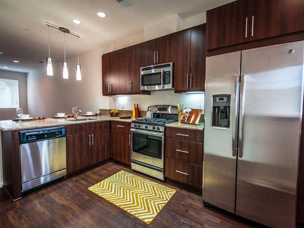 a kitchen with stainless steel appliances and wooden cabinets at The Vines at Riverpark, LLC, California