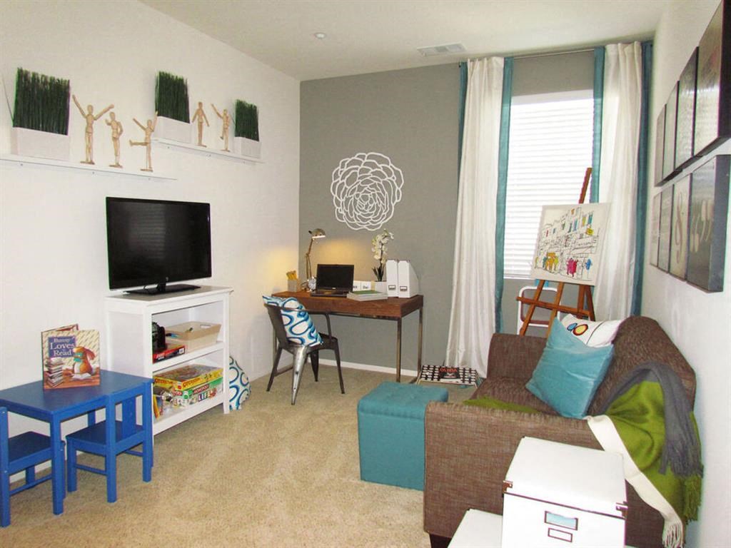 a living room with a couch and a desk and a tv at The Vines at Riverpark, LLC, Oxnard