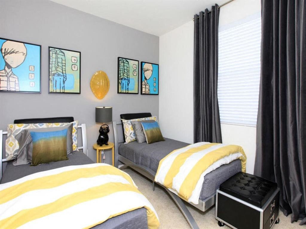 a bedroom with two twin beds with yellow and gray bedding at The Vines at Riverpark, LLC, Oxnard California