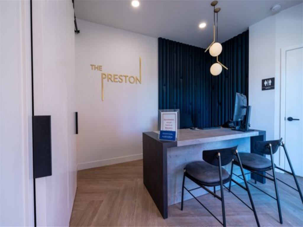a desk and chairs in a room with the logo on the wall  at The Preston at Hillsdale, San Mateo, California