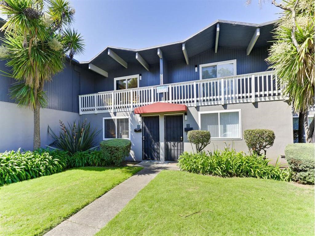the front of a blue house with a yard and a red umbrella at The Preston at Hillsdale, San Mateo, CA