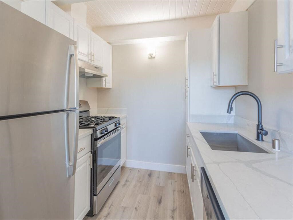 a kitchen with white cabinets and a stainless steel refrigerator  at The Preston at Hillsdale, San Mateo, CA