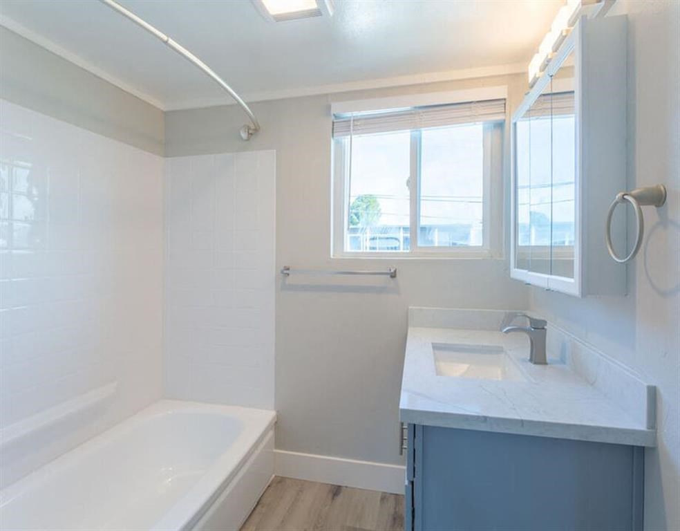 a white bathroom with a tub and a sink and a window at The Preston at Hillsdale, California
