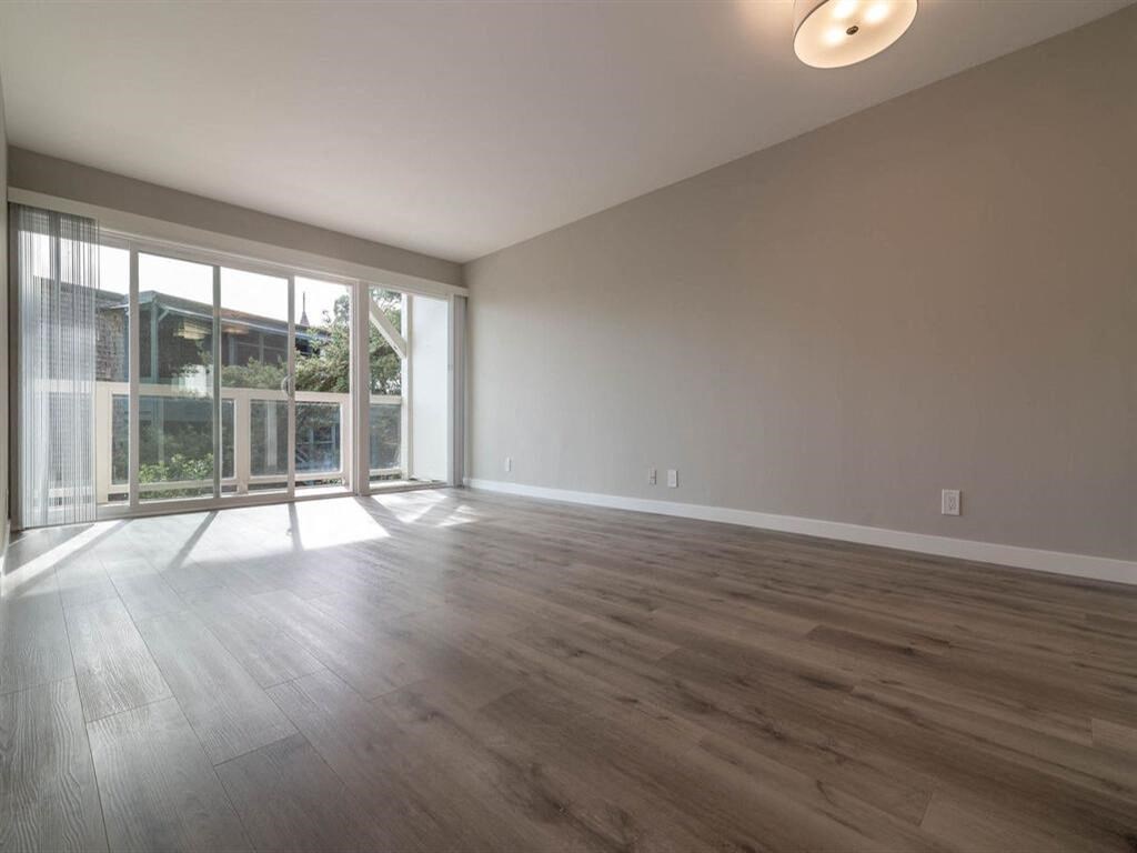 the living room of an empty house with wood flooring and a balcony at The Pier at Sausalito, Sausalito California
