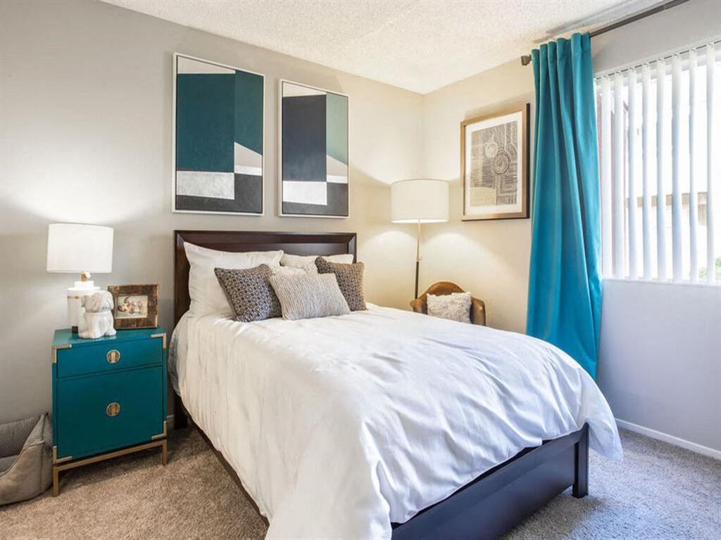 a bedroom with a white bed and blue curtains at Parc Medallion LLC, Union City, 94587