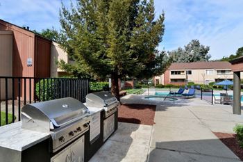 two grills and picnic tables in a courtyard with a pool and buildings at Parc Medallion LLC, Union City, CA 94587