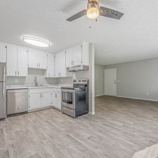 an empty kitchen with white cabinets and a ceiling fan at The Arches Apartments, El Cajon California