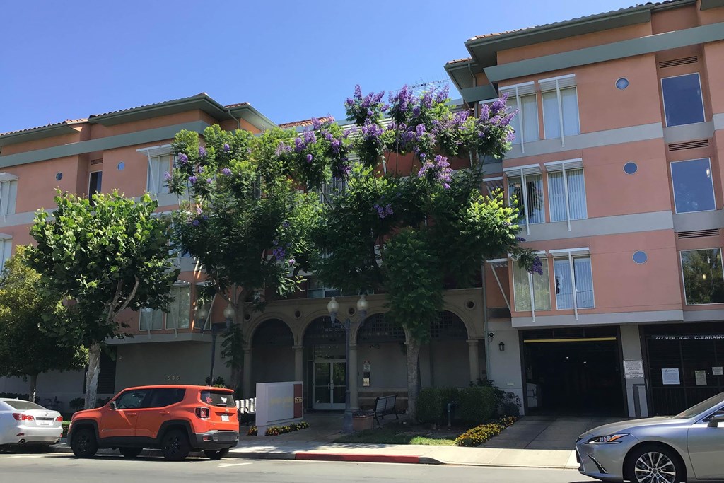 A Red Car Is Parked In Front Of a Building at Atrium Garden Apartment Homes, LLC, San Jose, CA