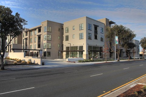 A modern apartment building with a parking lot in front at Catalyst Mountain View, Mountain View, CA