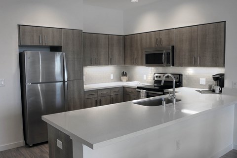 A modern kitchen with a stainless steel refrigerator and a white countertop.