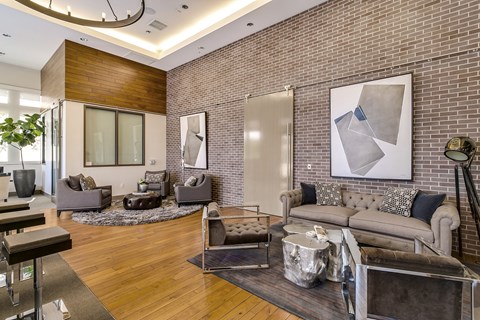 A modern living room with a grey couch and a large abstract painting on the wall.