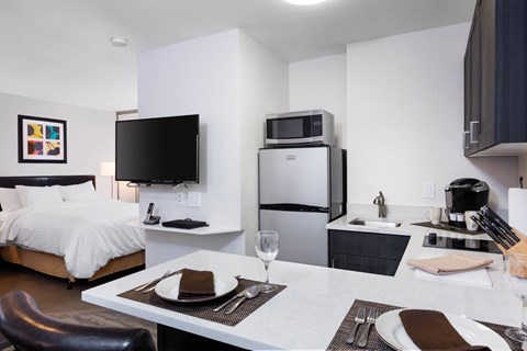 A modern kitchen and dining area with a bed and a refrigerator. at The Maddox Sunnyvale Apartments, California