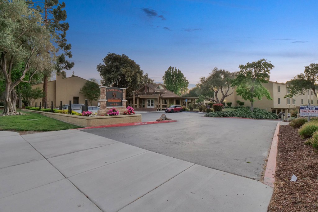 a street with a driveway and houses in the background at Summerwood Apartments, California