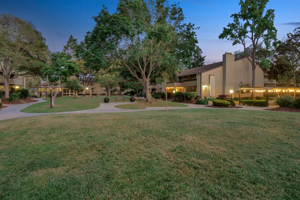 a building with trees and grass in front of it at Summerwood Apartments, Santa Clara, CA