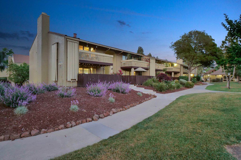 a building with a sidewalk and a garden in front of it at Summerwood Apartments, California