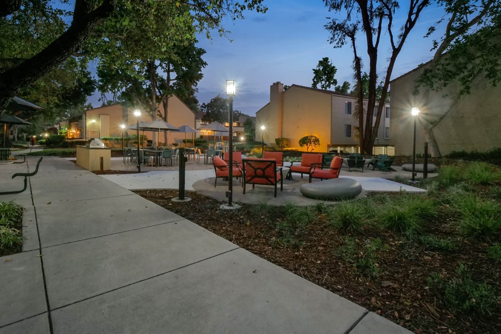 a courtyard with tables and chairs at night at Summerwood Apartments, Santa Clara, CA 95050