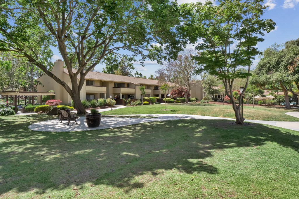 a grassy area with trees and a building in the background at Summerwood Apartments, California, 95050