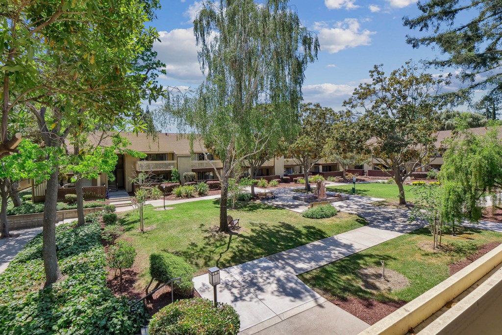a courtyard with trees and grass and a building in the background at Summerwood Apartments, California
