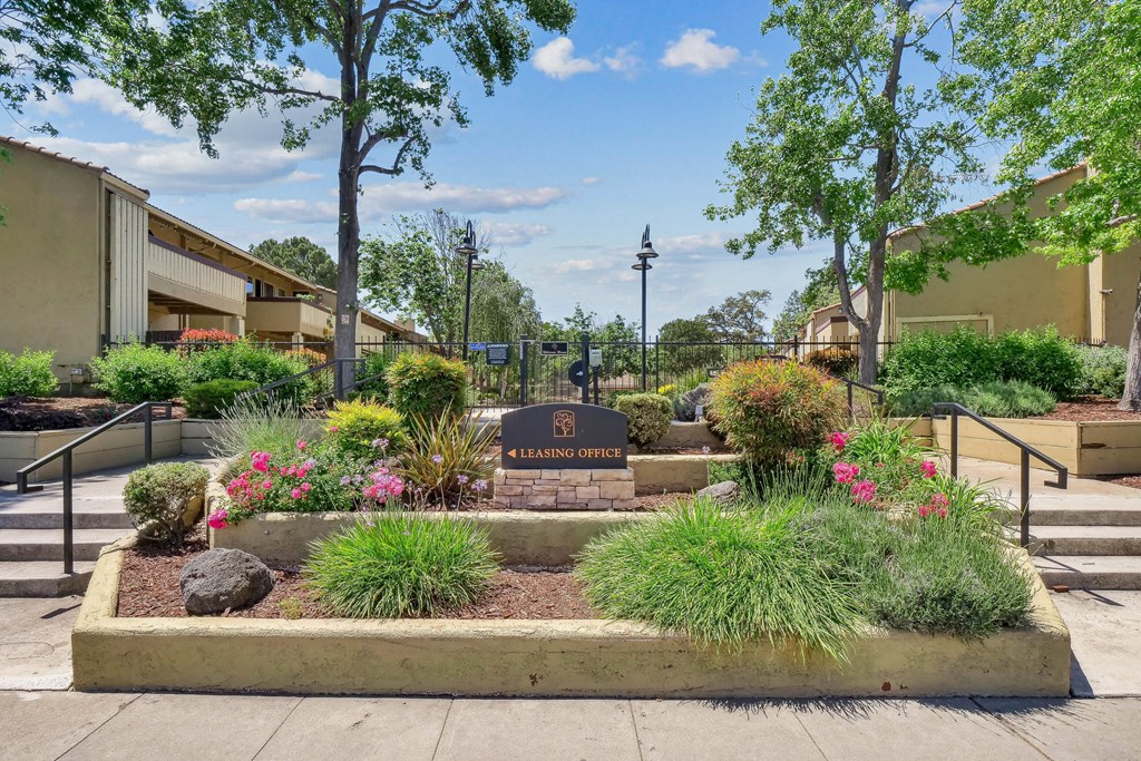 a community garden with flowers and trees and a sign at Summerwood Apartments, California