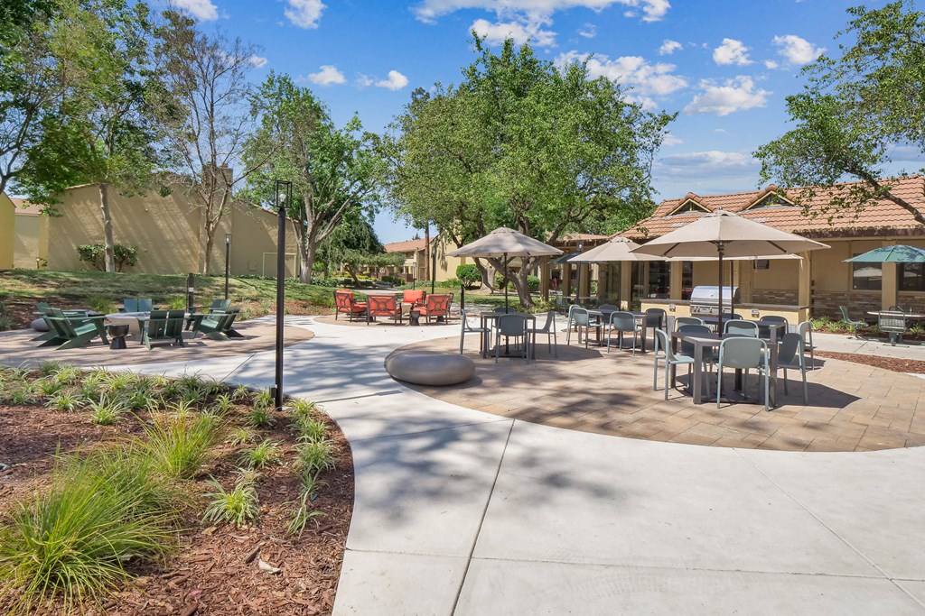 a patio with tables and chairs and umbrellas at Summerwood Apartments, Santa Clara