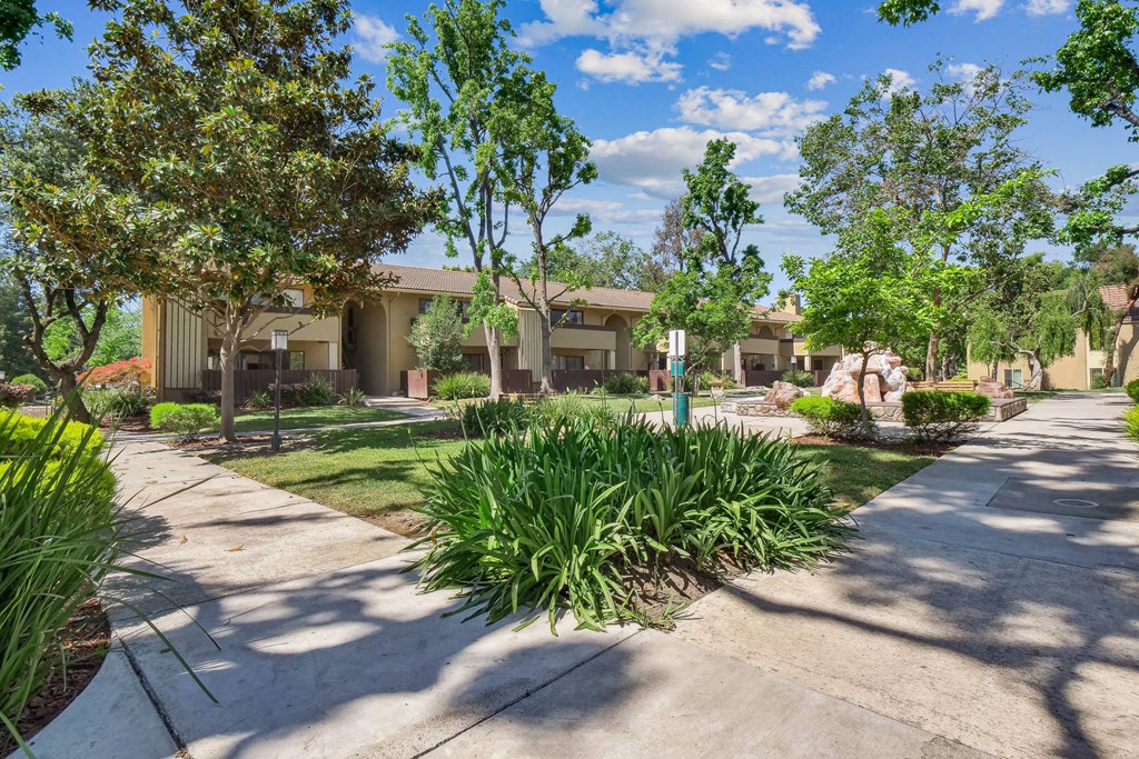 a garden with a fence and a house in the background at Summerwood Apartments, Santa Clara